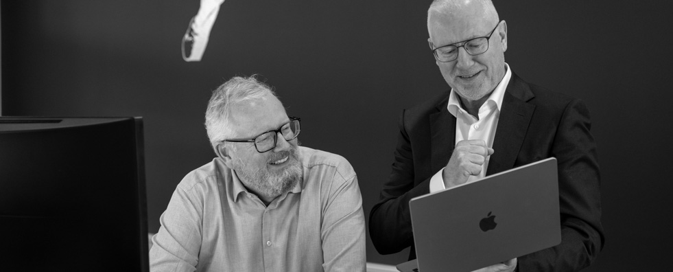 two people looking at a apple laptop