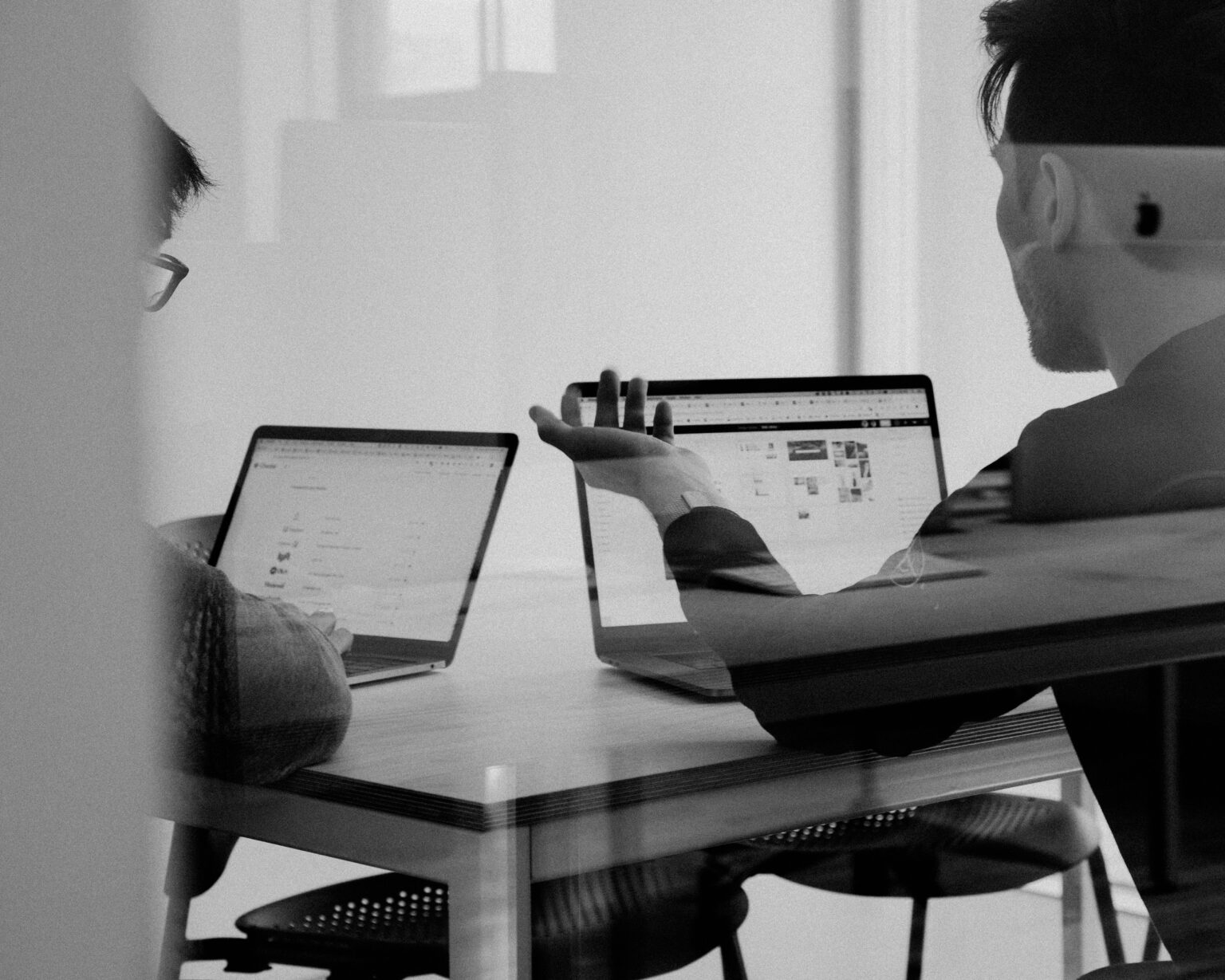 Two IT professionals with their laptops open.