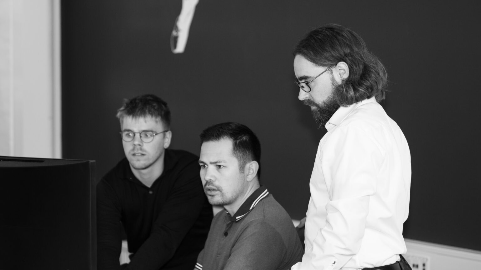 three men looking at a pc screen